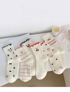 Flat lay of five white mid-calf socks with cute cartoon embroidery and lace trims