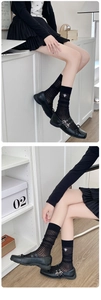 Close-up of black mesh striped calf socks with delicate white insect embroidery details