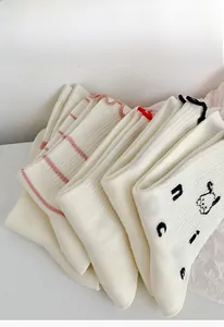 Detail of white cotton socks with cute cartoon embroidery and ruffled edges in a stack