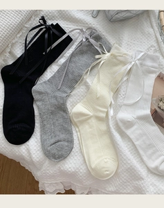 Flat lay of cotton rib-knit socks with silk bows in black, grey, cream, and white