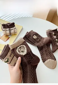 Détail de chaussettes marron vintage avec broderie ours et poignets à volants décoratifs