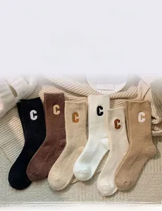 Close-up of ribbed wool socks featuring letter C embroidery in six neutral earth tones
