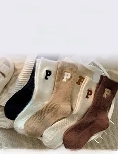 Detail of five thick wool socks with P embroidery and vertical knit texture in a tray
