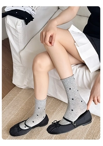 Detailed view of grey polka dot crew socks paired with black bow Mary Jane shoes