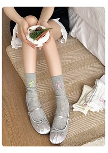 Détail de chaussettes grises avec broderie nœud et texture côtelée respirante