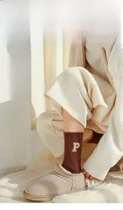Close-up of warm wool sock with P letter embroidery and plush slippers detail