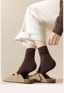 Detail von dunkelbraunen Baumwollsocken mit Rippmuster, getragen mit Wildleder-Clogs