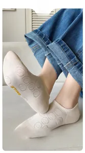 Close-up of beige cotton no-show socks featuring a yellow Smile embroidery detail