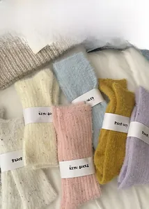Close-up of five colorful plush winter crew socks with fuzzy texture and brand packaging