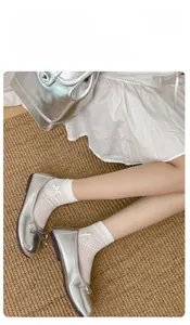 Details von weißen Baumwollsocken mit Schleifen kombiniert mit silbernen Schuhen