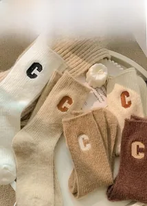 Detailed view of warm wool blend socks with embroidered C logo in earthy tones