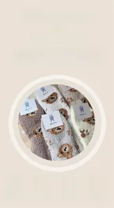 Close-up of thick coral fleece socks with cute cartoon bear patterns and soft textures