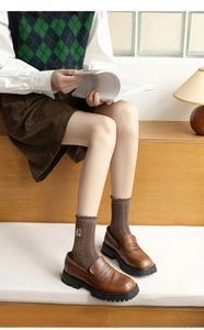 Gros plan de chaussettes torsadées marron avec motif ours et mocassins en cuir vintage