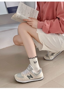 Detail of cream white mid-calf socks with black wave edges and bow embroidery