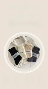 Dettaglio di quattro paia di calze a coste nei colori nero, crema, beige e grigio scuro