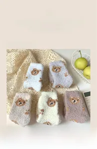 Detailed macro view of five colorful fluffy coral fleece socks with cute bear embroidery
