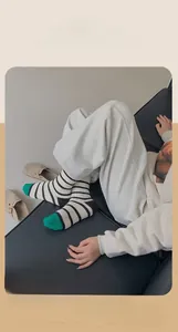 Detail of warm black and white striped crew socks with green tip on a leather sofa