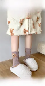 Close-up of cozy coral fleece socks with cute bear pattern for winter indoor warmth