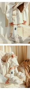 Detail of cream white wool socks with embroidered C letter and plush fuzzy slippers