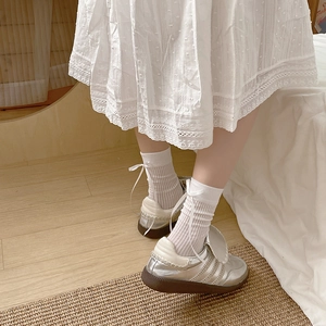 White ribbon bow cotton mesh socks paired with silver sneakers on a cozy wooden floor