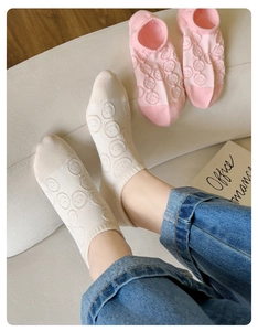 Close-up of cotton no-show socks featuring a textured knit smiley face pattern