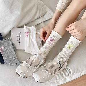 Chaussettes à nœuds brodés et ballerines blanches dans un décor de maison cosy