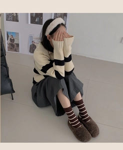 Detail of brown striped cotton socks paired with cozy brown fuzzy slippers for winter style