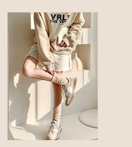 Dettaglio calzini beige a coste spesse abbinati a scarpe da ginnastica e shorts in denim