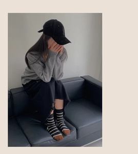 Detail shot of striped crew socks paired with a gray knit cardigan and black skirt