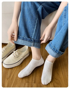 Detailed view of white cotton low cut socks featuring a knitted jacquard smiley face pattern