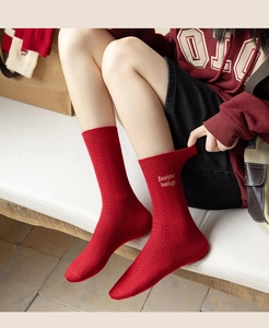 Detail of red cashmere socks with Keep your headup yellow embroidery and ribbed texture