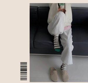 Close-up of striped cotton socks with green toe tips and beige suede clogs shoes