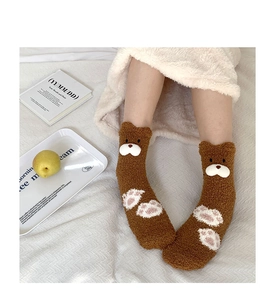 Detail of thick coral fleece socks featuring cute brown bear design and cozy texture