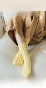 Close-up of bright yellow winter socks with thick cable knit texture on soft sofa