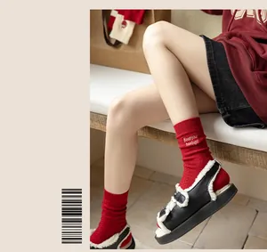 Detail of red cashmere socks with white Keep your head up embroidery and knit texture
