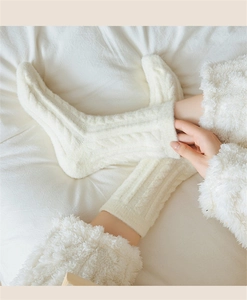 Detail of cream cable-knit warm fleece socks on bed showing cozy plush texture