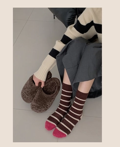 Detail of warm striped crew socks with contrasting toe and cozy slippers