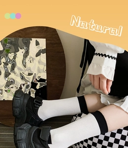 Close-up of white mid-calf socks with black ribbed edges paired with platform sandals