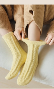 Detail of warm yellow cable knit socks showing thick thermal texture and mid-tube style