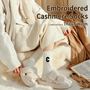 Thick beige wool socks with C embroidery shown with plush slippers for winter warmth
