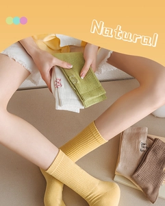 Close-up of cotton ribbed crew socks with Good Things Arrive embroidery in earthy tones