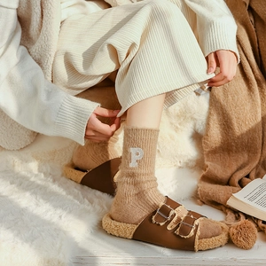 Brown faux fur slippers paired with khaki knit socks featuring white letter P embroidery