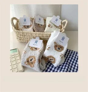 Detail view of plush coral fleece socks with cute cartoon bear and branded card tags