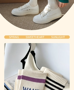 Detailed macro view of white cotton ribbed crew socks with purple stripes and letters