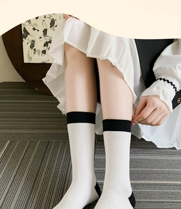 Close-up of ribbed cotton mid-calf socks in off-white with black contrasting heel and cuff