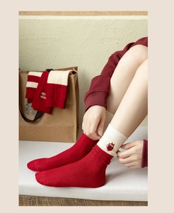 Detail of red and cream knit socks with cute owl embroidery and thick ribbed texture