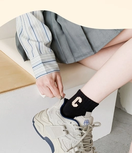 Detail of black ribbed cotton mid-tube socks with C letter embroidery and chunky sneakers
