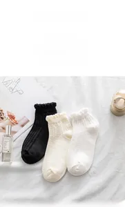 Close-up of three pairs of frilly lace ankle socks in black, beige, and white colors