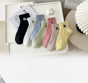 Macro detail of combed cotton socks with letter H embroidery in seven assorted pastel colors