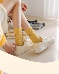 Detail of yellow ribbed cotton socks with Wild Flower Herbs embroidery and white sneakers